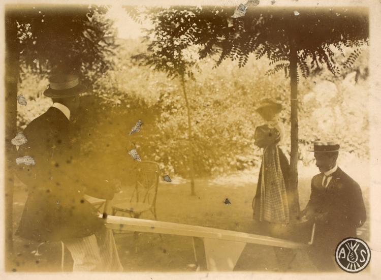 Dos homes jugant amb un balancí davant la mirada d'una noia. S.l.