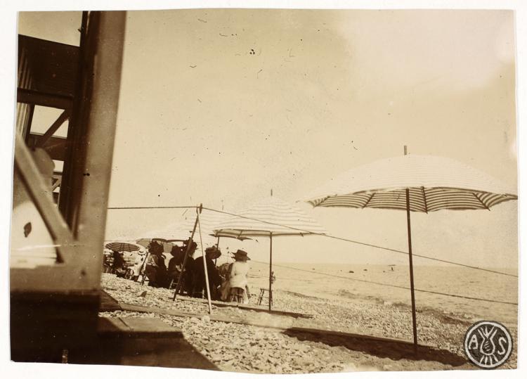 Grup de banyistes sota un parasol en una platja sense identificar. S.l.