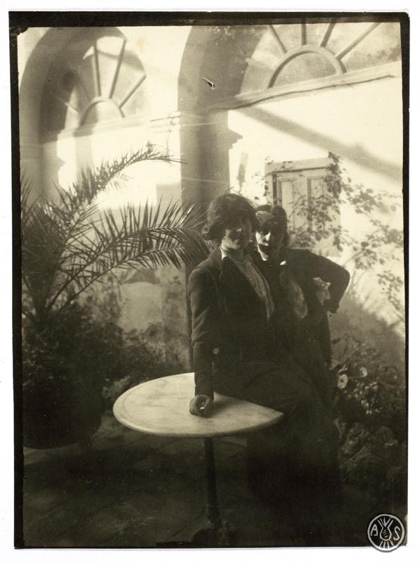 Dues dones al voltant d'una taula rodona en un jardí. S.l.