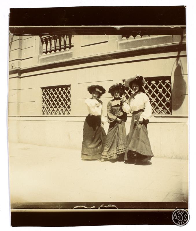 Tres dones davant la façana d'un edifici. S.l.