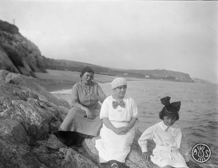 Dues dones i Maria Costa sobre unes roques a Caldes d'Estrac