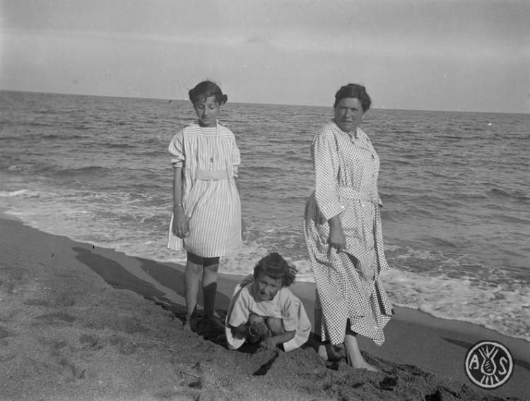 Dues nenes i una dona en una platja a Caldes d'Estrac