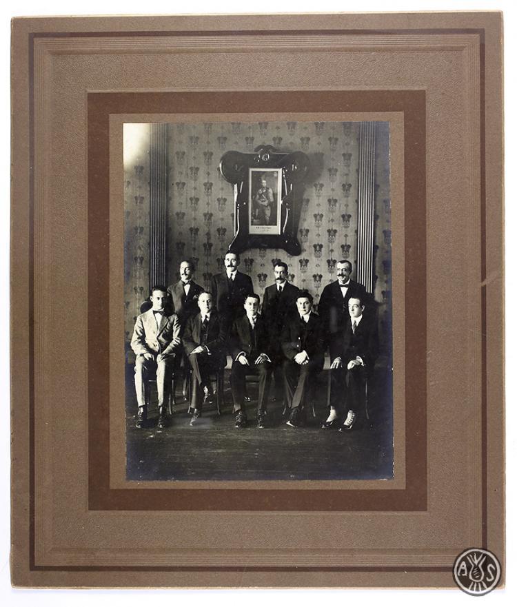 Retrat d'un grup d'homes sense identificar. Al fons el retrat del rei Alfons XIII. Sabadell.