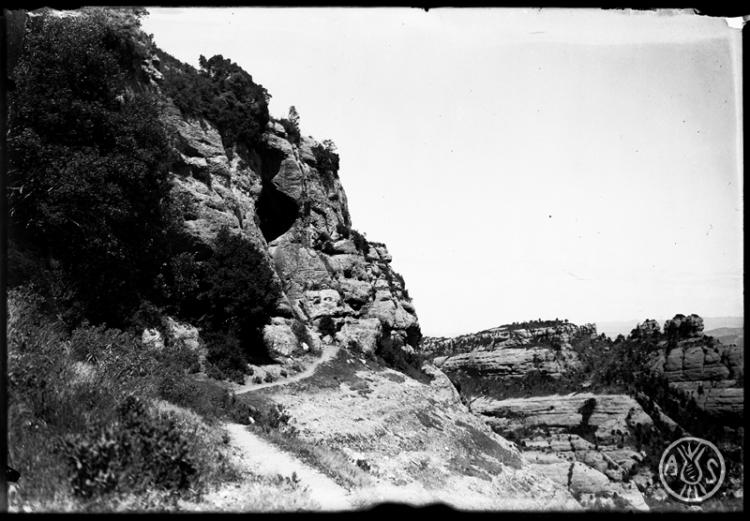 Camí d'accés i diaclassa de la cova Simanya. Al fons els Emprius. Parc Natural de Sant Llorenç del Munt