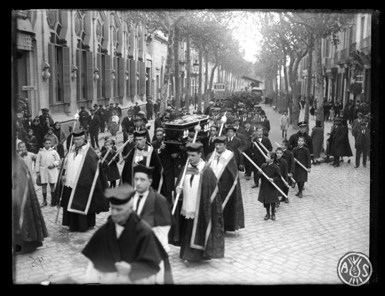 Enterrament de Josep Gorina Pujol. Clergues de la Santíssima Trinitat i el fèretre portat a hombros a la Rambla de Sabadell al seu pas pel teatre Euterpe. Sabadell