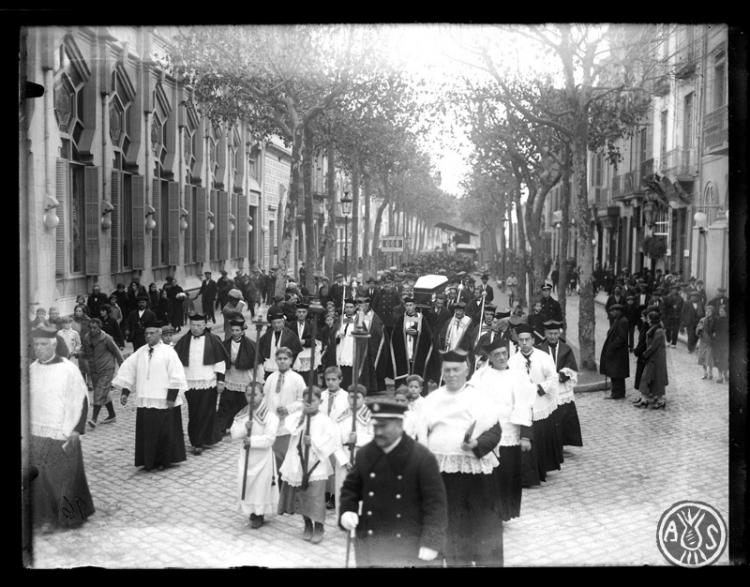 Enterrament de Josep Gorina Pujol. Clergues de la Santíssima Trinitat i el fèretre portat a les espatlles per la Rambla de Sabadell al seu pas pel teatre Euterpe. Sabadell