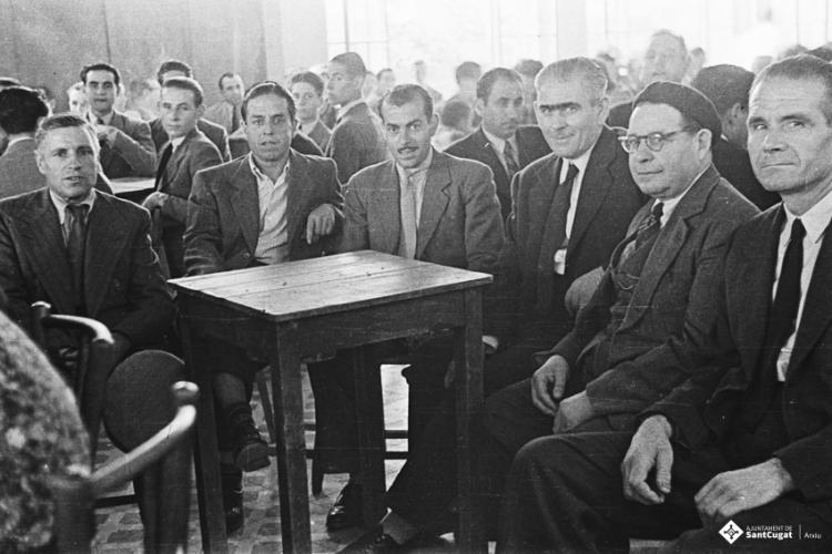 Actes de la festa inaugural de la restaurada Societat Coral La Unió Santcugatenca. Un grup d'homes asseguts, a la sala del cafè de la Unió.