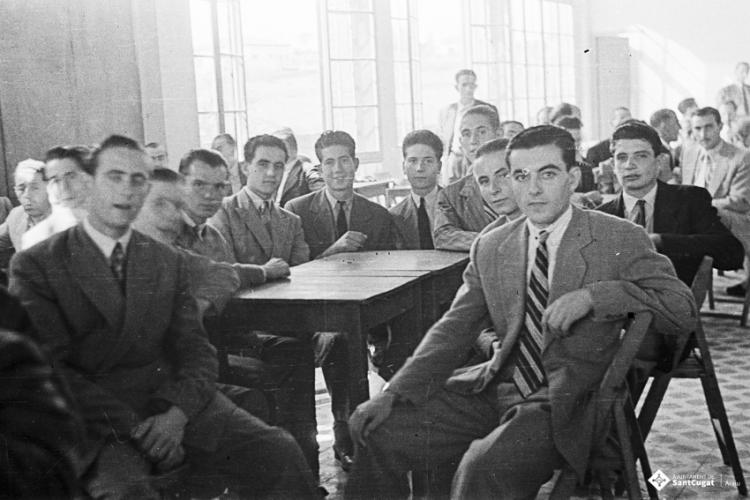 Actes de la festa inaugural de la restaurada Societat Coral La Unió Santcugatenca. Un grup de joves asseguts, a la sala del cafè de la Unió.