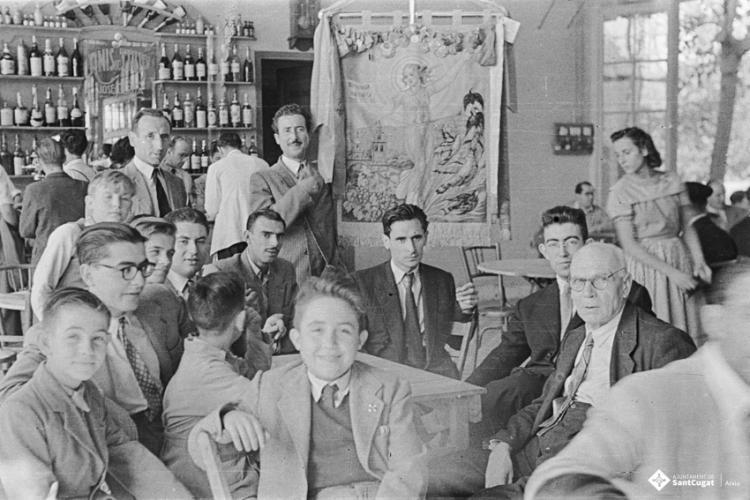 Actes de la festa inaugural de la restaurada Societat Coral La Unió Santcugatenca. Retrat de grup amb l'estendard a la sala del cafè de la Unió.