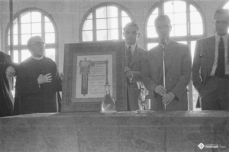 Actes de la festa inaugural de la restaurada Societat Coral La Unió Santcugatenca. Lliurament d'un pergamí - recordatori emmarcat al mossèn.