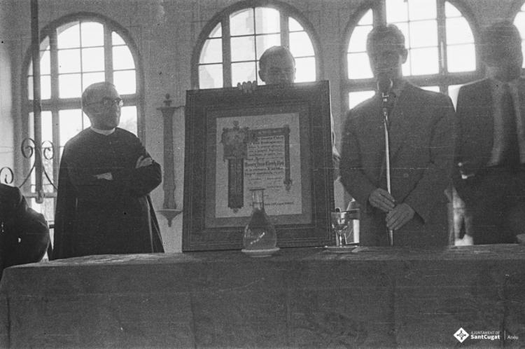 Actes de la festa inaugural de la restaurada Societat Coral La Unió Santcugatenca. Lliurament d'un pergamí - recordatori emmarcat al mossèn.