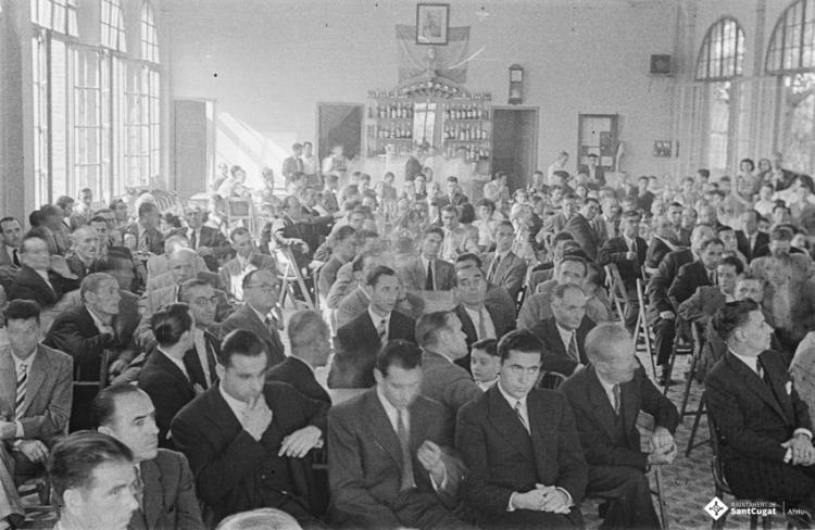 Actes de la festa inaugural de la restaurada Societat Coral La Unió Santcugatenca. Benedicció del local. Assistents a la sala del cafè de la Unió.