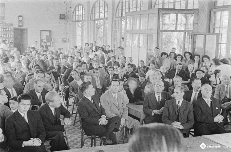 Actes de la festa inaugural de la restaurada Societat Coral La Unió Santcugatenca. Benedicció del local. Assistents a la sala del cafè de la Unió.