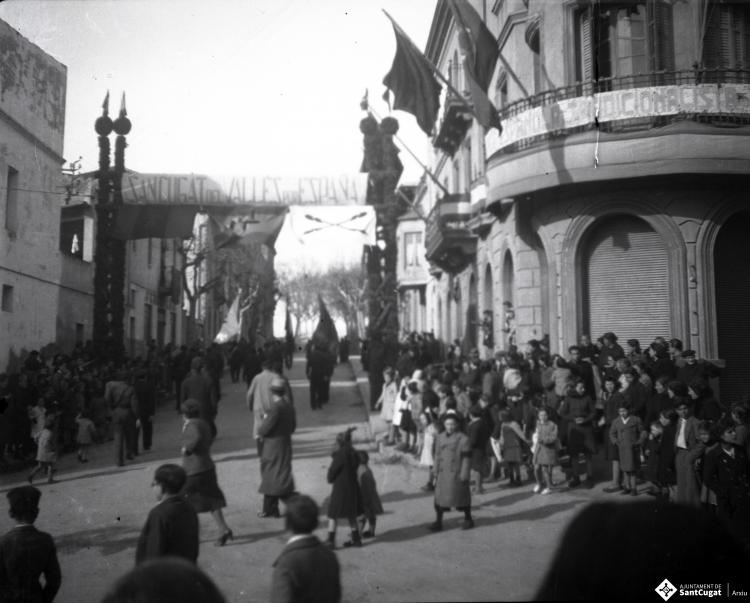 Celebració als Quatre Cantons davant de la seu de la Falange de Sant Cugat del Vallès i desfilada amb banda de músics als Quatre Cantons.