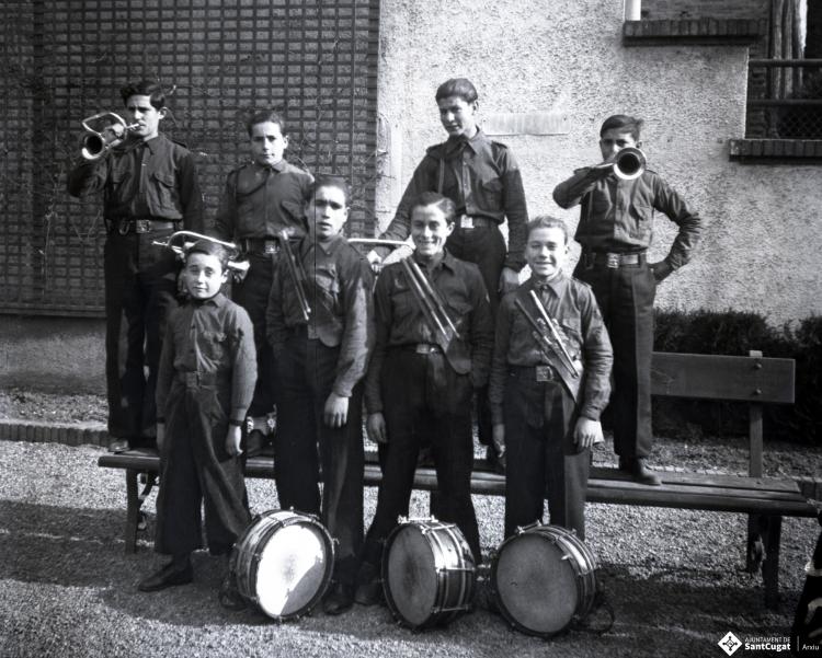 Celebració als Quatre Cantons davant de la seu de la Falange de Sant Cugat del Vallès i desfilada amb banda de músics als Quatre Cantons.