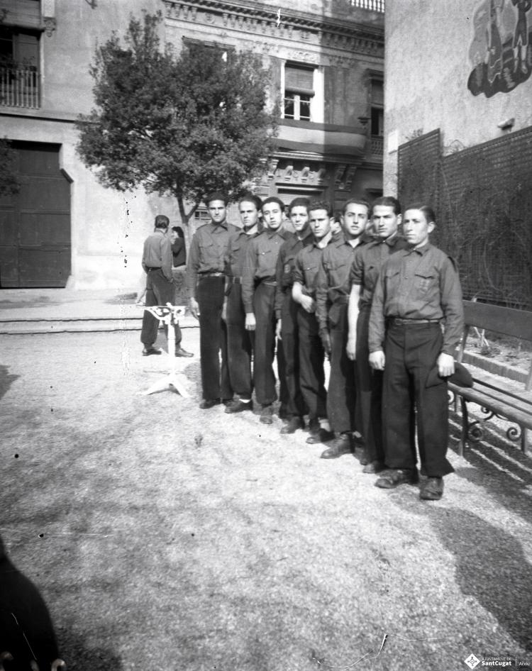 Celebració als Quatre Cantons davant de la seu de la Falange de Sant Cugat del Vallès i desfilada amb banda de músics als Quatre Cantons.