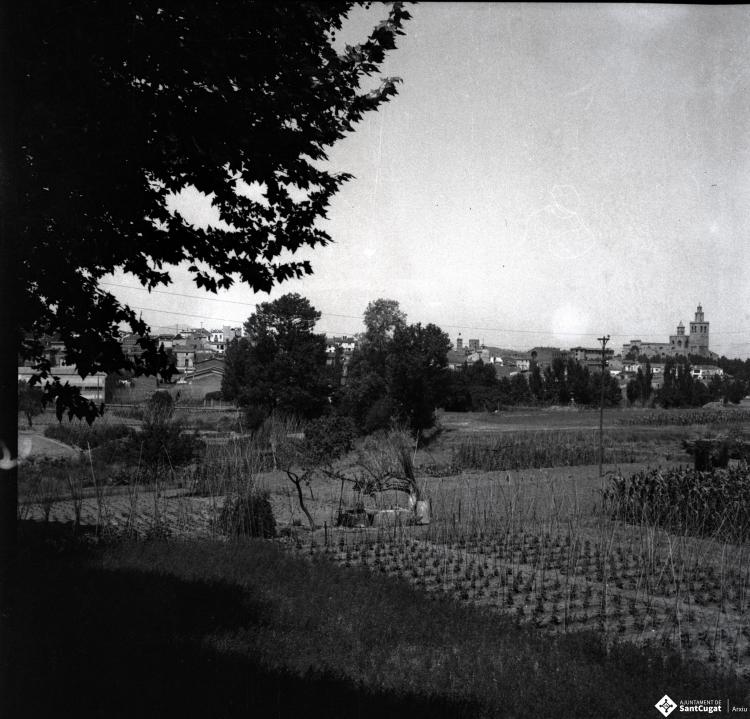 Vista del Monestir i el nucli de la vila, des dels horts de la masia de Can Ganxet de la Riera.