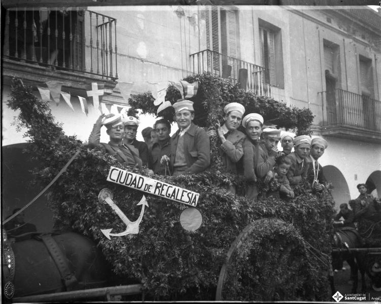 Festa de Sant Antoni Abat. Carruatge enramat amb forma de vaixell, amb el rètol: Ciutat de Regalèssia, amb els membres de la Penya Regalèssia vestits de mariners durant la passada.