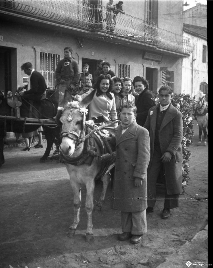 Festa de Sant Antoni Abat. Retrat de un grup de joves dalt d'un carro al seu pas per la plaça de Barcelona.