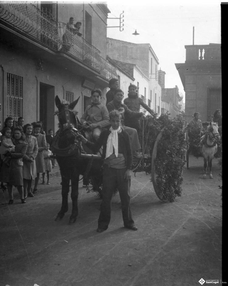 Festa de Sant Antoni Abat. Retrat de un grup de joves dalt d'un carro al seu pas per la plaça de Barcelona.