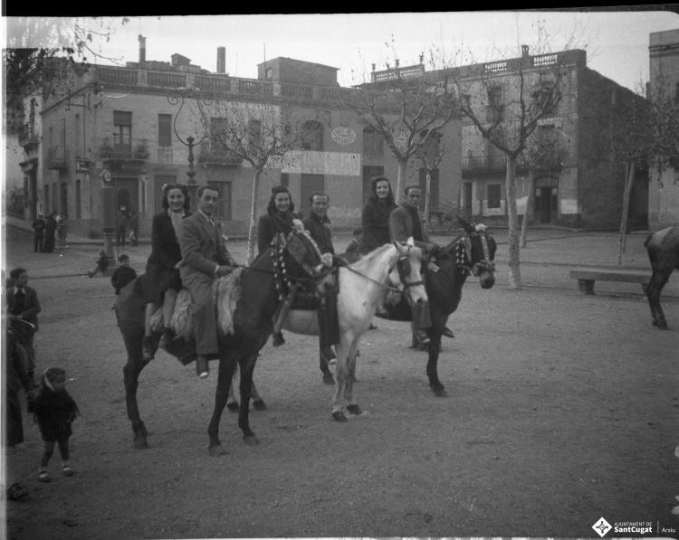 Festa de Sant Antoni Abat. Retrat  de tres parelles  joves muntant a cavall, a la plaça d'Octavià, prop del brollador de benzina i del carrer Major.