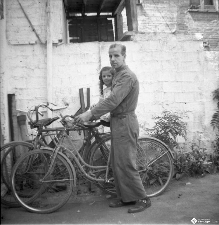 Retrat d'Elisabet Cabanas sobre una bicicleta sostinguda  pel seu pare, Joan Cabanas.