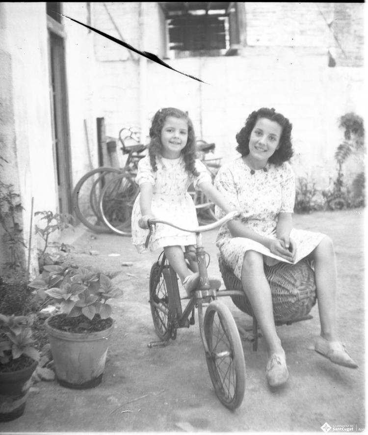 Retrat de l'Elisabet  Cabanas sobre una bicicleta i de la Maria Quiñonero asseguda sobre el sidecar de vímet.