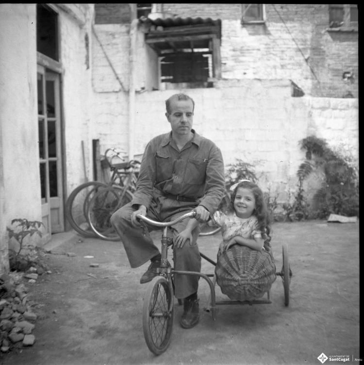Retrat del Joan Cabans en bicicleta i de l'Elisabet asseguda en el sidecar de vímet d'aquesta.