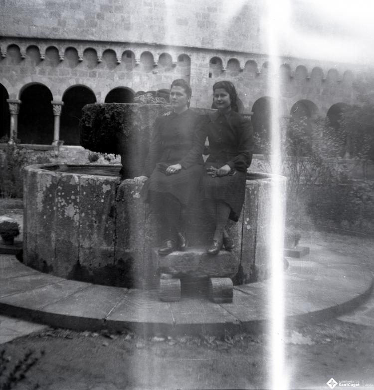 Retrat de dues noies assegudes a la font del claustre.