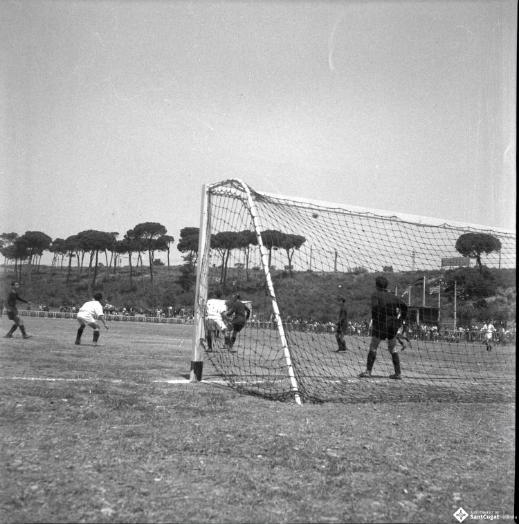Activitats festives, partit de futbol. Ubicació no identificada, a prop hi ha una catenària d'un tren.