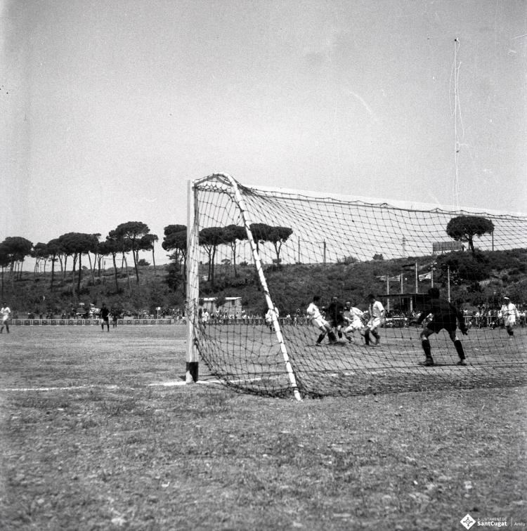 Activitats festives, partit de futbol. Ubicació no identificada, a prop hi ha una catenària d'un tren.