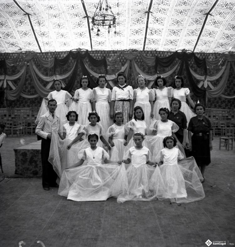 Festa Major. Ball a l'envelat, retrat d'un grup de nenes, probablement de la secció infantil de l'Esbart Dansaire, acompanyades per  Manuel Farrés i dues dones uniformades.