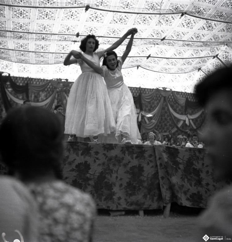 Festa Major. Noies ballant a l'escenari de l'envelat, probablement de la secció infantil de l'Esbart Dansaire, acompanyades per  Manuel Farrés i dues dones uniformades.