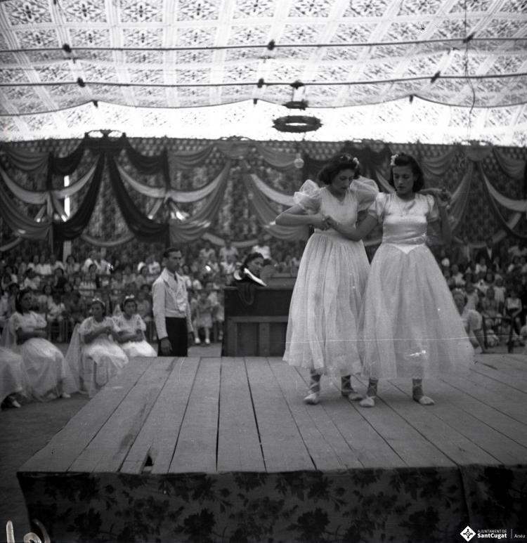 Festa Major. Noies ballant a l'escenari de l'envelat, probablement de la secció infantil de l'Esbart Dansaire, acompanyades per  Manuel Farrés i dues dones uniformades.