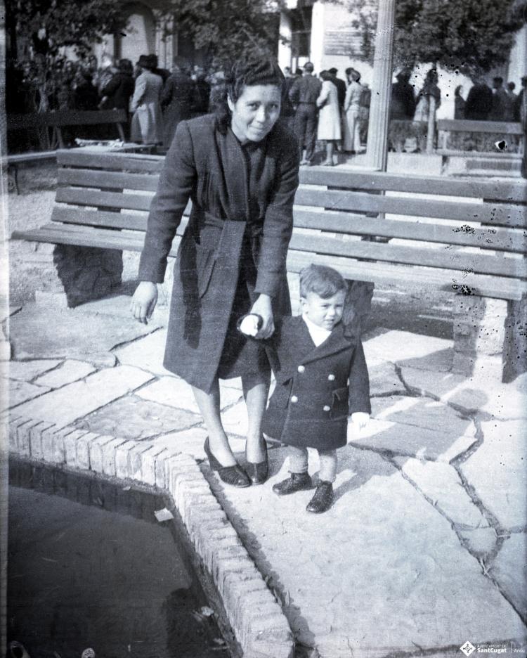 Celebració davant de la seu de la Falange a Cal Barbany. Retrat d'una dona amb un infant a la plaça del Quatre Cantons.