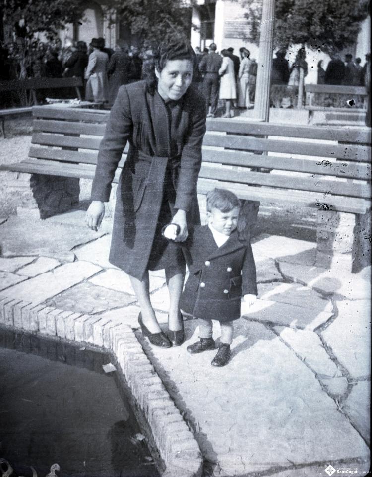 Celebració davant de la seu de la Falange a Cal Barbany. Retrat d'una dona amb un infant a la plaça del Quatre Cantons.
