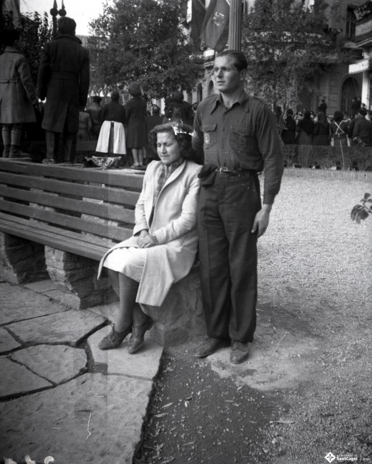 Celebració davant de la seu de la Falange a Cal Barbany.Retrat d'una parella, al fons el públic d'esquena a l'escena assisteix a la desfilada davant de la seu de la falange.