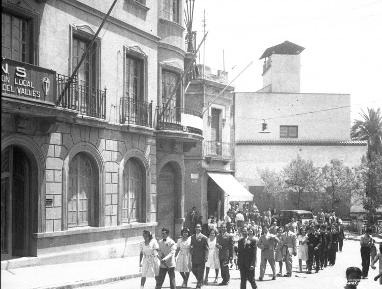 Desfilada de les parelles de balladors del Paga-li Joan al seu pas pels Quatre Cantons davant de la seu de la Central Nacional-Sindicalista.