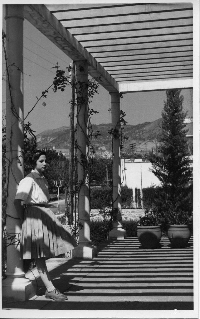 Nena recolzada a la columna d'una pèrgola d'una torre d'estiueig