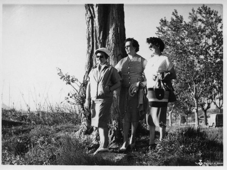 Tres dones d'excursió al costat d'un arbre