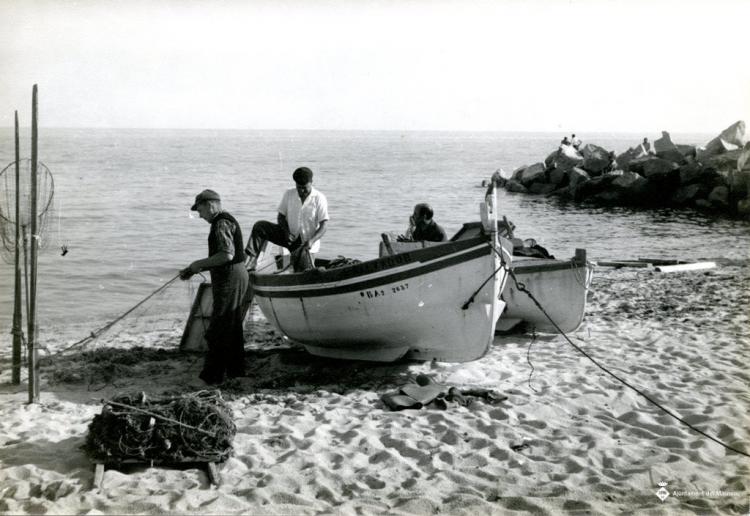 Pescadors arreglant les xarxes al costat de les barques a la platja