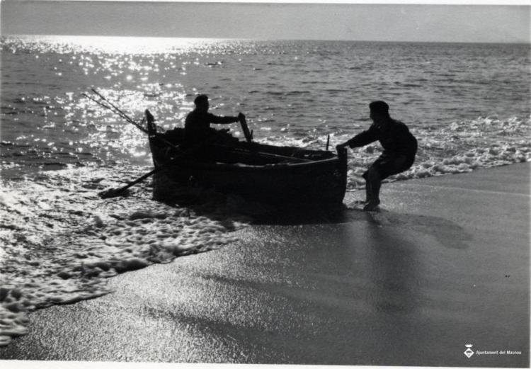 Un home varant una barca de rems a la platja del Masnou