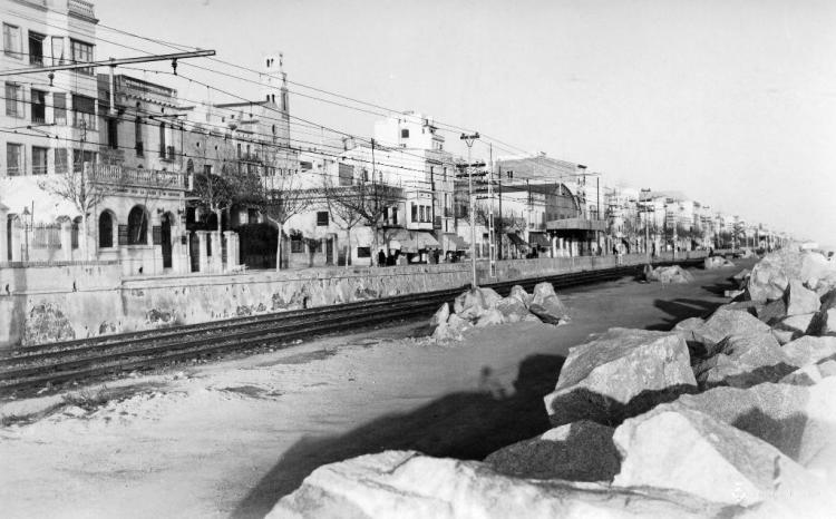 Vies de tren i façana marítima del Masnou des d'unes roques de la platja