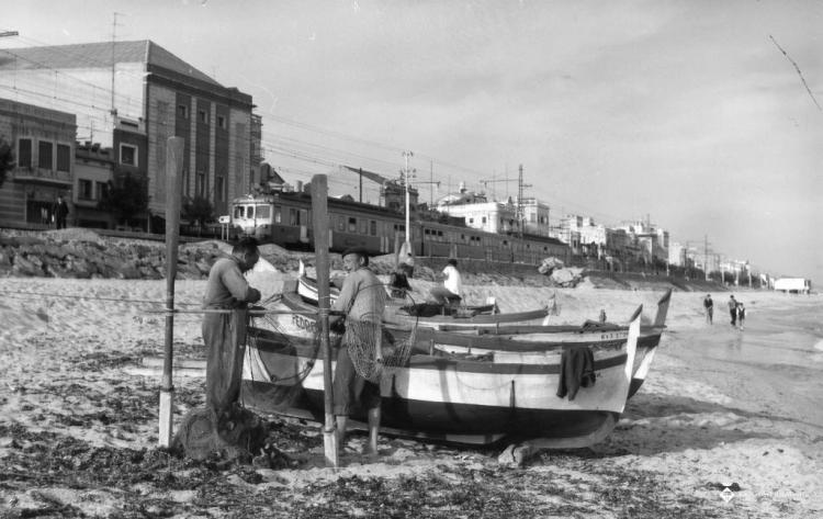 Pescadors treballant al costat de les barques varades a la platja
