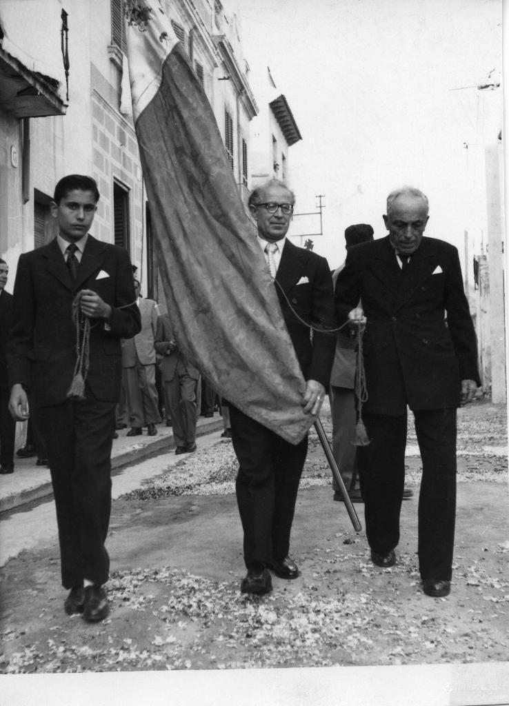 Tres homes amb una bandera durant la processó de Corpus