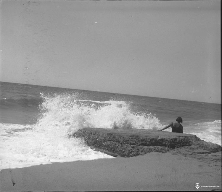 Dona en una roca a la platja