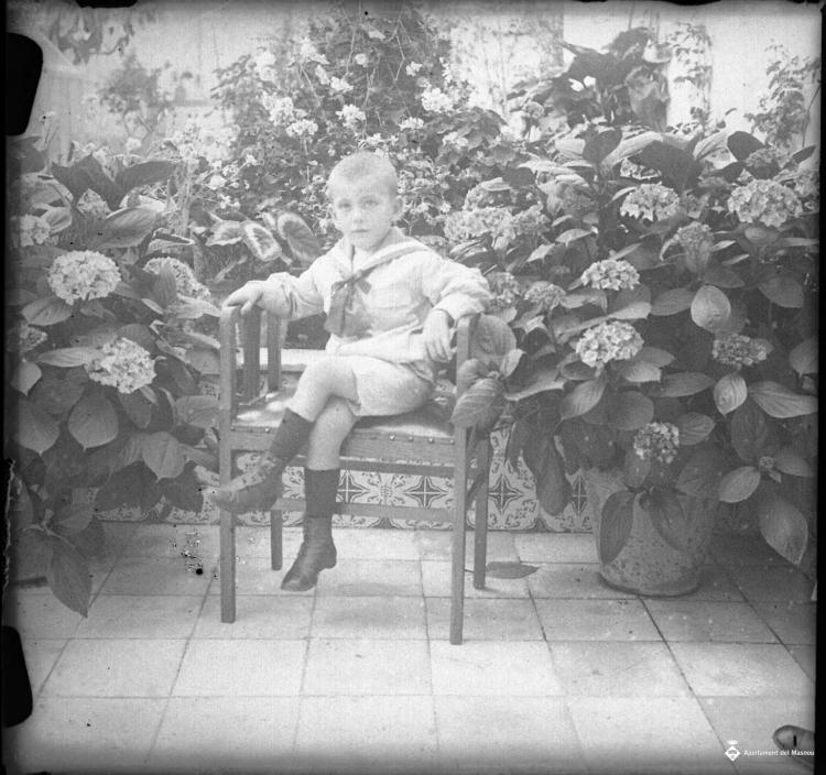 Retrat d'un nen assegut en una cadira al jardí