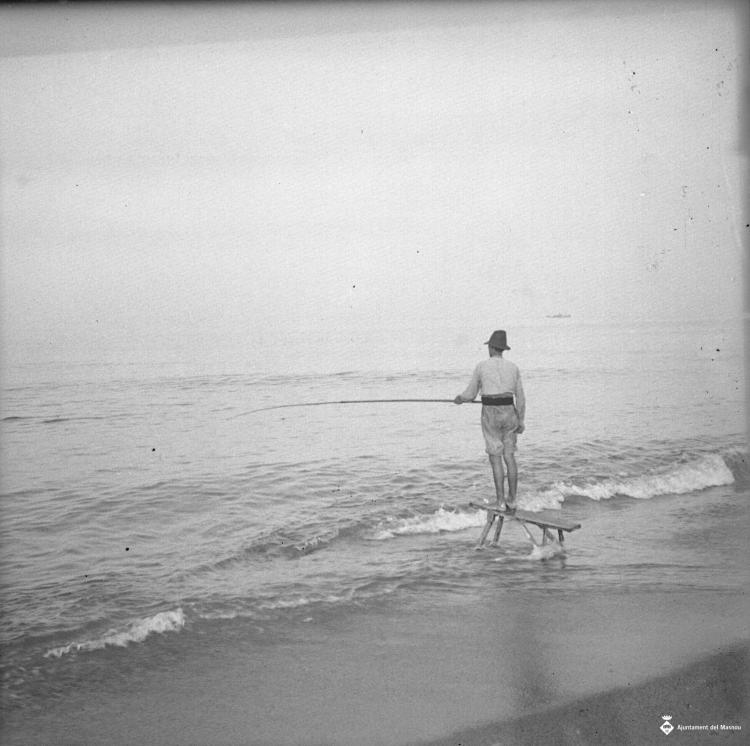 Home sobre una cadira pescant a la platja