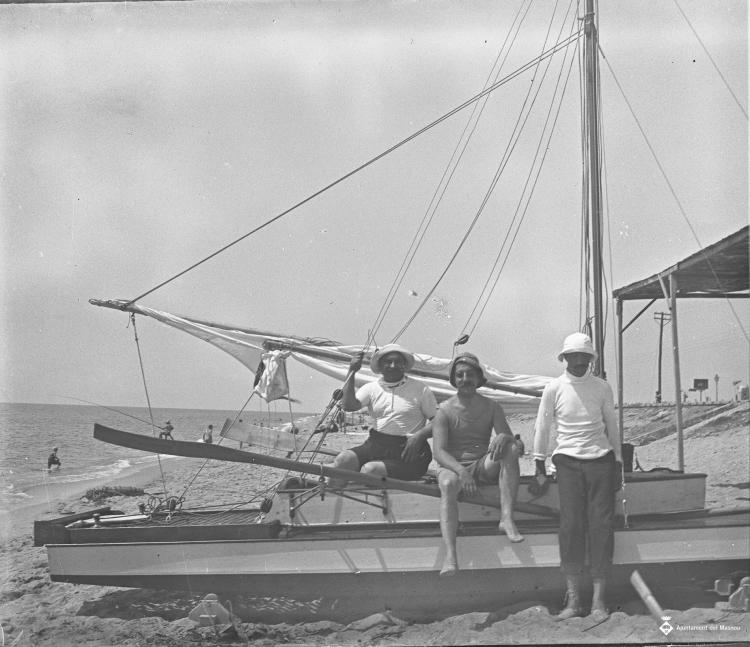 Tres homes asseguts sobre un pati de vela