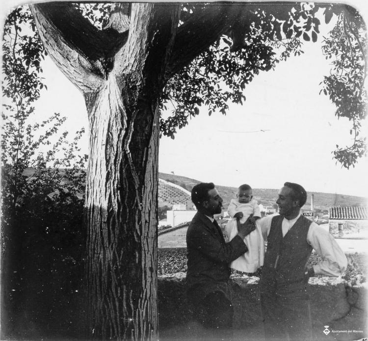 Retrat de dos homes amb nadó al costat d'un arbre
